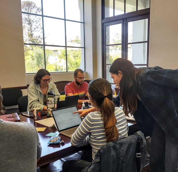 An instructor leans over a participant's shoulder to help troubleshoot on the participant's laptop.