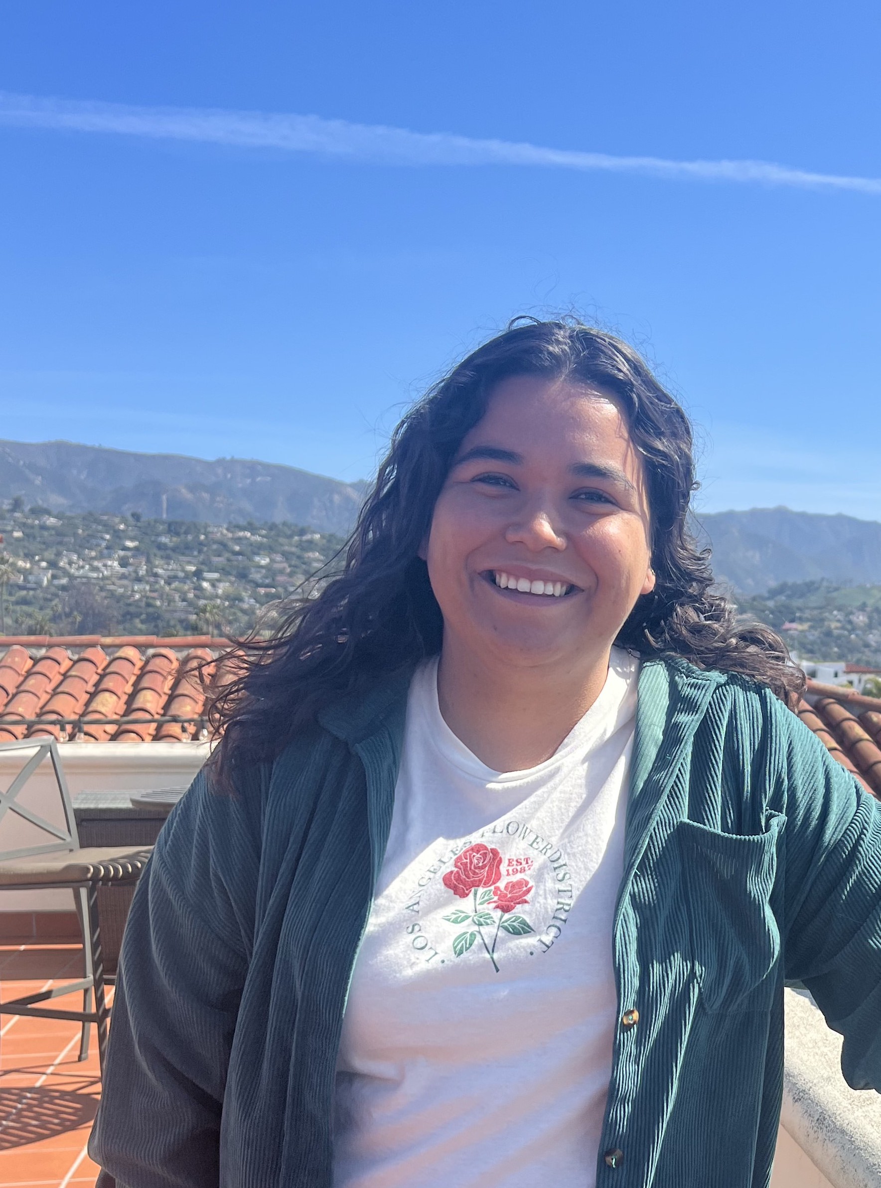 A woman stands on a third floor terrace patio in Santa Barbara, CA on a sunny day. 