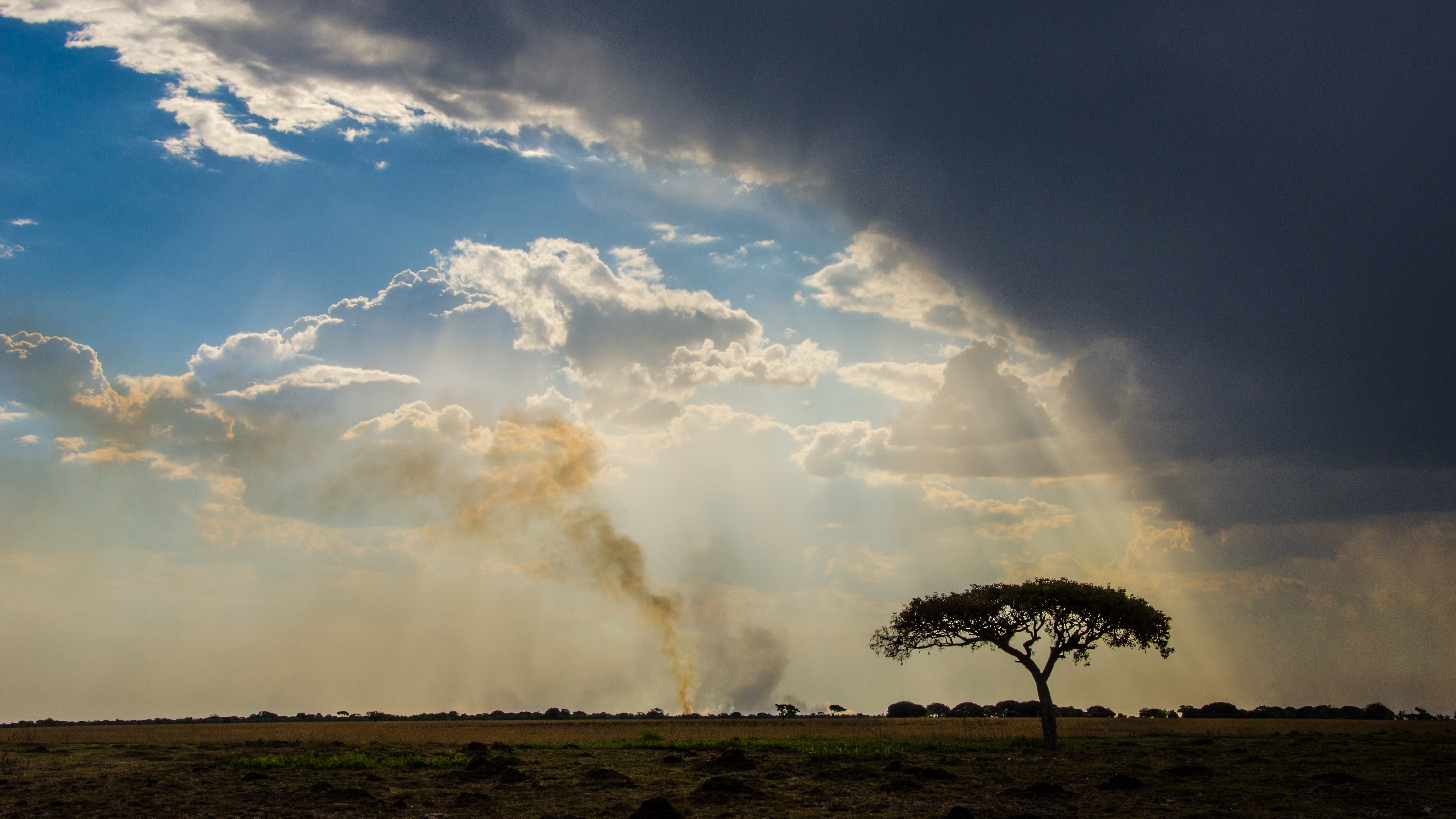 a landscape Zambia with clouds and trees and smoke