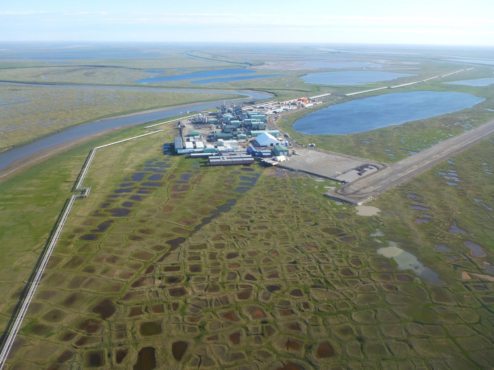Photo by Ben Jones. Infrastructure built on ice-rich permafrost in northern Alaska. We know that the permafrost is ice-rich because we can see the ice-wedge polygons on the ground surface.