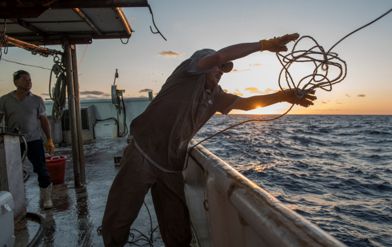 man throws rope over fishing boat