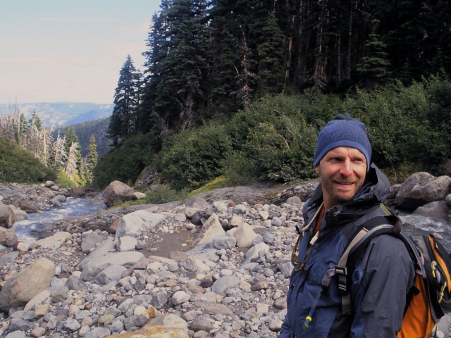 man standing over alpine river