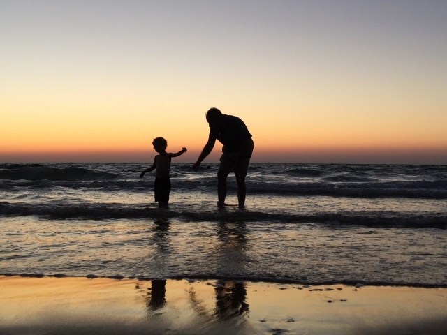 Man and child wading in ocean