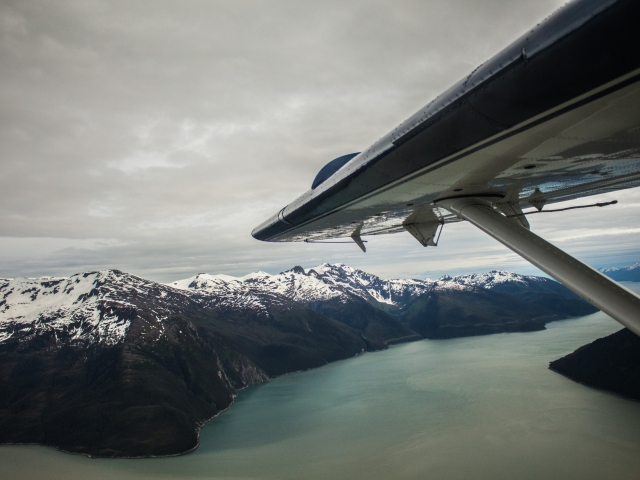 Plane wing over Alaskan fjord