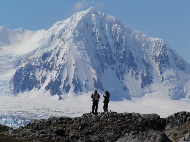 Two people standing in front of snowy mountain