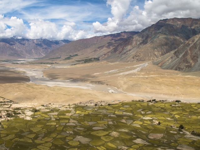 Aerial of mountains and dry valley, with green land in foreground