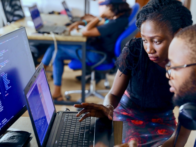 Two people of color reviewing data on a laptop screen