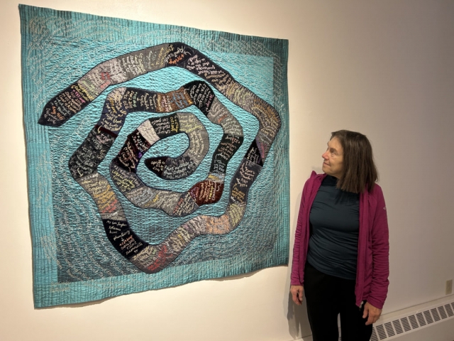 Bonnie Peterson next to embroidered art piece