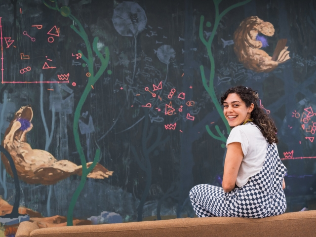 Leila smiles in front of her mural 