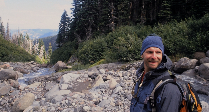 man standing over alpine river