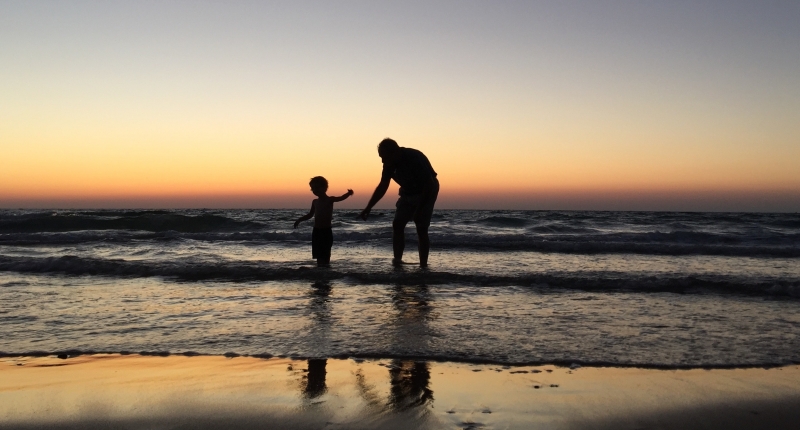 Man and child wading in ocean