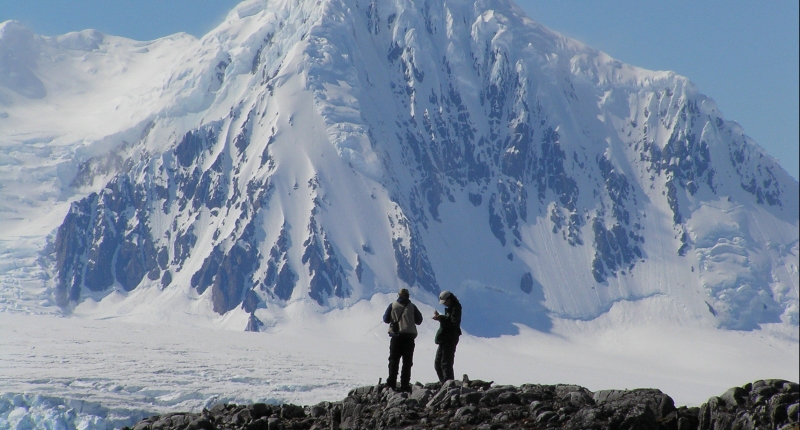 Two people standing in front of snowy mountain