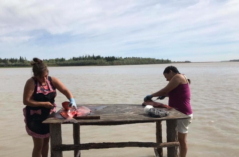 Two women cutting and cleaning salmon