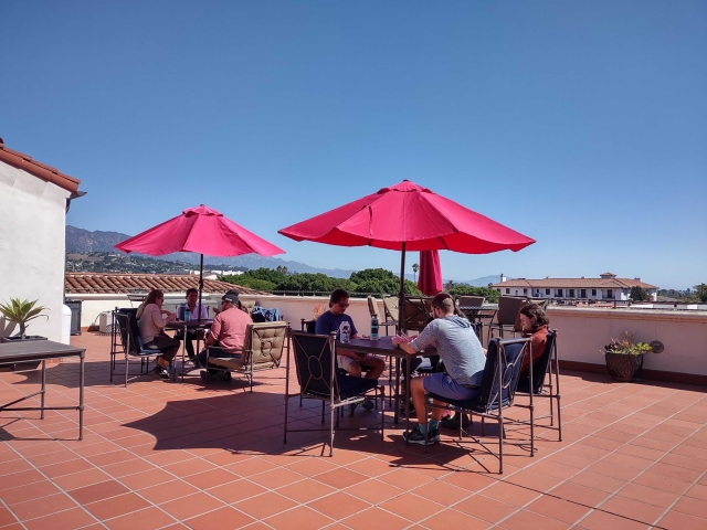 Red umbrellas shade two tables on the sunny NCEAS terrace. 