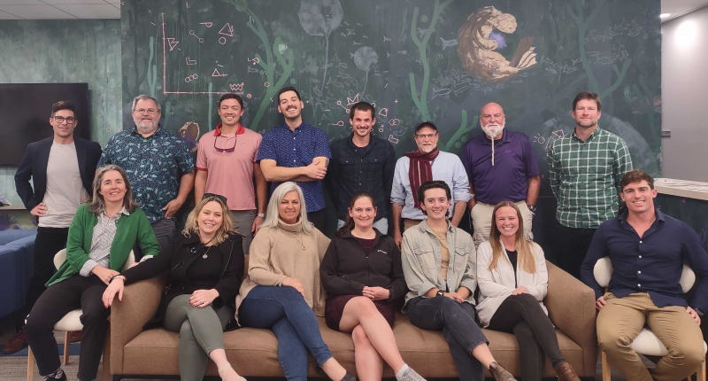 Group photo of the GEI Harris working group, standing in front of an ocean-themed mural at NCEAS. 